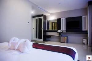 1 dormitorio con 1 cama blanca grande y TV en The Harbour Front Hotel en Surat Thani