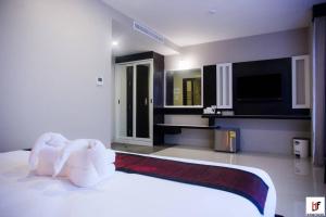 ein Schlafzimmer mit einem großen weißen Bett und einem TV in der Unterkunft The Harbour Front Hotel in Surat Thani