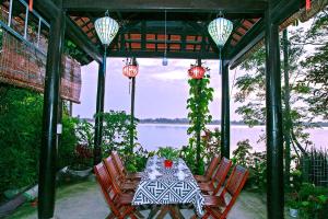 a table and chairs with a view of the water at Thu Bon Riverside Homestay in Hoi An