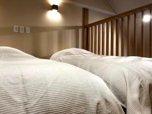 2 camas en un dormitorio con sábanas blancas en Nozawa Onsen Utopia, en Nozawa Onsen