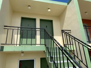 a building with two green doors and a staircase at Casa De Pedro Entire Apartment in Mangilao