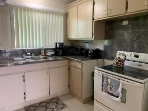 La cuisine est équipée de placards blancs et d'un four avec plaques de cuisson. dans l'établissement Casa De Pedro Entire Apartment, à Mangilao