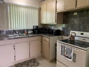 uma cozinha com armários brancos e um forno com placa de fogão em Casa De Pedro Entire Apartment em Mangilao