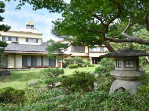 a garden with a stone lantern in front of a building at Hotel Hagoromo in Shizuoka