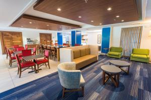 a lobby with tables and chairs and a restaurant at Holiday Inn Express & Suites Wilmington-University Center, an IHG Hotel in Wilmington