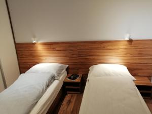 two beds in a room with a wooden wall at Apartament71 in Płock