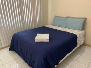 a bed with a blue blanket and a towel on it at Casa De Pedro- Entire Villa in Mangilao