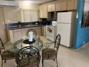 a kitchen with a glass table with chairs and a refrigerator at Entire Private Villa- Casa De Pedro in Mangilao