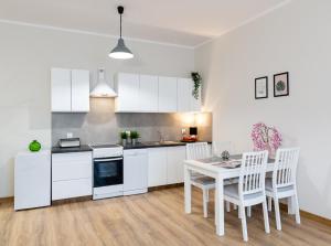 uma cozinha com armários brancos e uma mesa e cadeiras em Lucky Place BASIC em Bielsko-Biala