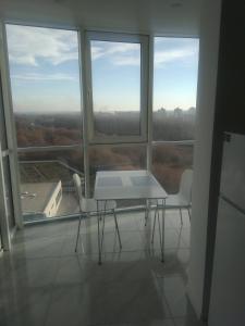 einen Tisch und zwei Stühle in einem Zimmer mit Fenstern in der Unterkunft Апартаменти Люкс in Chmelnyzkyj