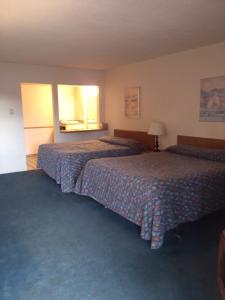 een hotelkamer met 2 bedden en 2 ramen bij High Chaparral Inn in Rocky Ford