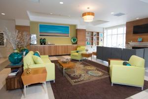 a living room with yellow and green furniture and a kitchen at Holiday Inn Morgantown-University Area, an IHG Hotel in Morgantown