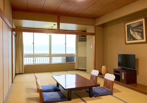 和歌山的住宿－新瓦卡日式旅館，客厅配有桌椅和电视。