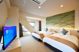 
a hotel room with two beds and a television at Oriental Suites Airport Osaka Rinku in Izumi-Sano

