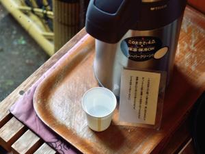 a cup of coffee on a wooden table with a coffee maker at Hotel Hagoromo in Shizuoka