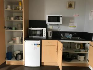 a kitchen with a microwave, refrigerator, and dishwasher at Beachend Bicheno in Bicheno