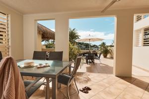 ein Esszimmer mit einem Tisch, Stühlen und einem Sonnenschirm in der Unterkunft Sea Change Beachfront Apartments in Trinity Beach