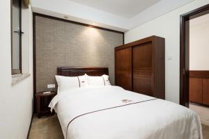 um quarto com uma grande cama branca e uma cabeceira em madeira em Iccssi Villa Haitang Bay Sanya em Sanya