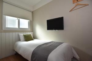 a bedroom with a bed with a flat screen tv on the wall at Hotel QB Dongdaemun Gallery in Seoul