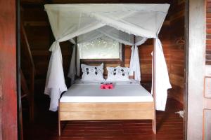 a bedroom with a canopy bed with red apples on it at LES CHALETS DE MELINDA in Nosy Be