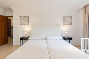 1 cama blanca grande en un dormitorio con 2 mesas en Apartamento Soho Málaga, en Málaga