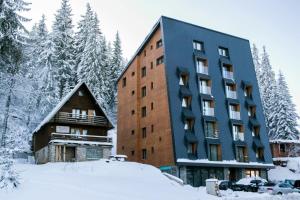 un gran edificio en la nieve con árboles en Alpin Apartments Jahorina, en Jahorina