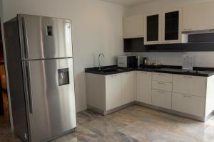 Una cocina con gabinetes blancos y un refrigerador de acero inoxidable. en Rawai Paradise, en Rawai Beach