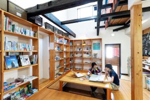 deux personnes assises à une table dans une bibliothèque dans l'établissement Cyclo No Ie, à Imabari