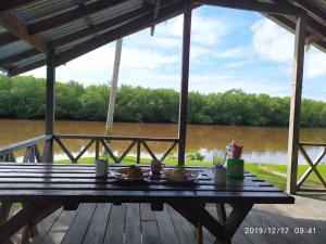 a picnic table on a deck with a view of a river at MB Camp Singkil in Gosongtelaga
