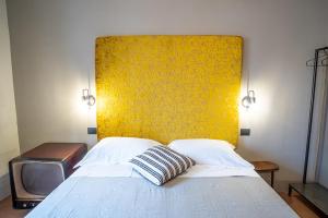 a bed with a yellow headboard and a tv at Casatorre dei Leoni Dimora Storica in Siena