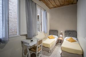 Habitación con 2 camas, escritorio y ventanas. en Casatorre dei Leoni Dimora Storica, en Siena