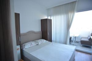 a bedroom with a white bed and a living room at Yeşilyurt Residence in Izmir