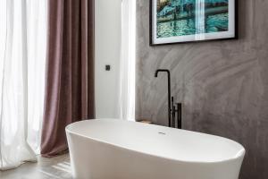 a white tub in a bathroom with a picture on the wall at One Shot Tabakalera House in Donostia-San Sebastián