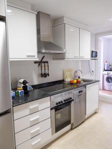 eine Küche mit weißen Schränken und Küchengeräten aus Edelstahl in der Unterkunft Playa Sol Apartment in Denia
