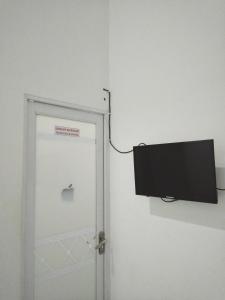 une porte en pomme avec une télévision fixée à un mur dans l'établissement Wisma Aira, à Ternate