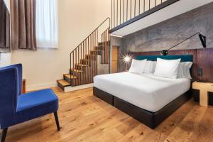 a bedroom with a bed and a blue chair at One Shot Tabakalera House in Donostia-San Sebastián