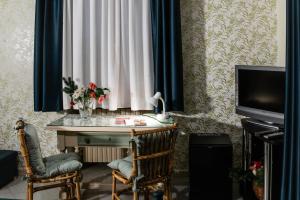 een kamer met een bureau, een gordijn en een televisie bij Santa Caterina da Siena B&B in Catania