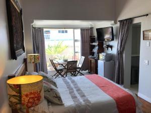 a bedroom with a bed and a table and a window at Baylight Accomodation in Mossel Bay