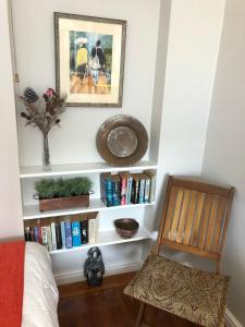 ein Schlafzimmer mit einem Bücherregal mit Büchern und einem Stuhl in der Unterkunft Baylight Accomodation in Mossel Bay