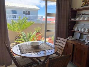 a table and chairs in a room with a balcony at Baylight Accomodation in Mossel Bay
