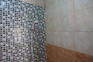 a shower in a bathroom with black and white tiles at RedDoorz @ Hotel Aulia Majene in Majene