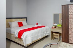 um quarto com uma cama grande e um cobertor vermelho em RedDoorz @ Hotel Grand Aulia Majene em Majene