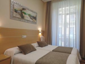una camera d'albergo con due letti e una finestra di Pensión Urumea a San Sebastián