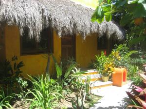 a small yellow house with a thatch roof at Unelma Bungalows in Bucer&iacute;as