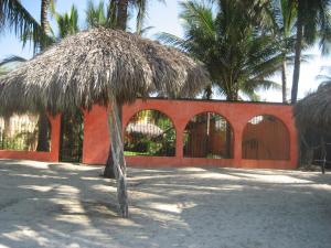 a building with a straw hut with palm trees at Unelma Bungalows in Bucerías