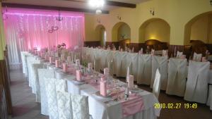 a row of tables and chairs in a room with pink candles at Hotel Koloniál Skalité in Skalité