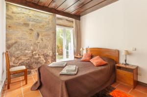 a bedroom with a bed and a stone wall at Quinta S. Romao do Neiva in Castelo do Neiva +24 photos