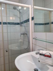 a bathroom with a shower and a white sink at Hotel Arena in Cologne