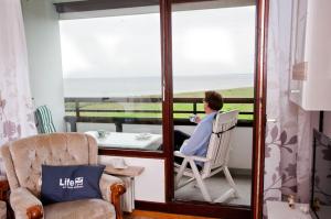 a person sitting in a chair on the balcony looking out at the ocean at Ferienwohnung in Damp Residenzblick an der Ostsee in Damp