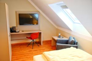 ein Schlafzimmer mit einem Bett, einem Stuhl und einem TV in der Unterkunft Walldorf Suites Boutique Hotel in Walldorf